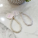 Pearl keychain on a marble surface with a small plant in the background