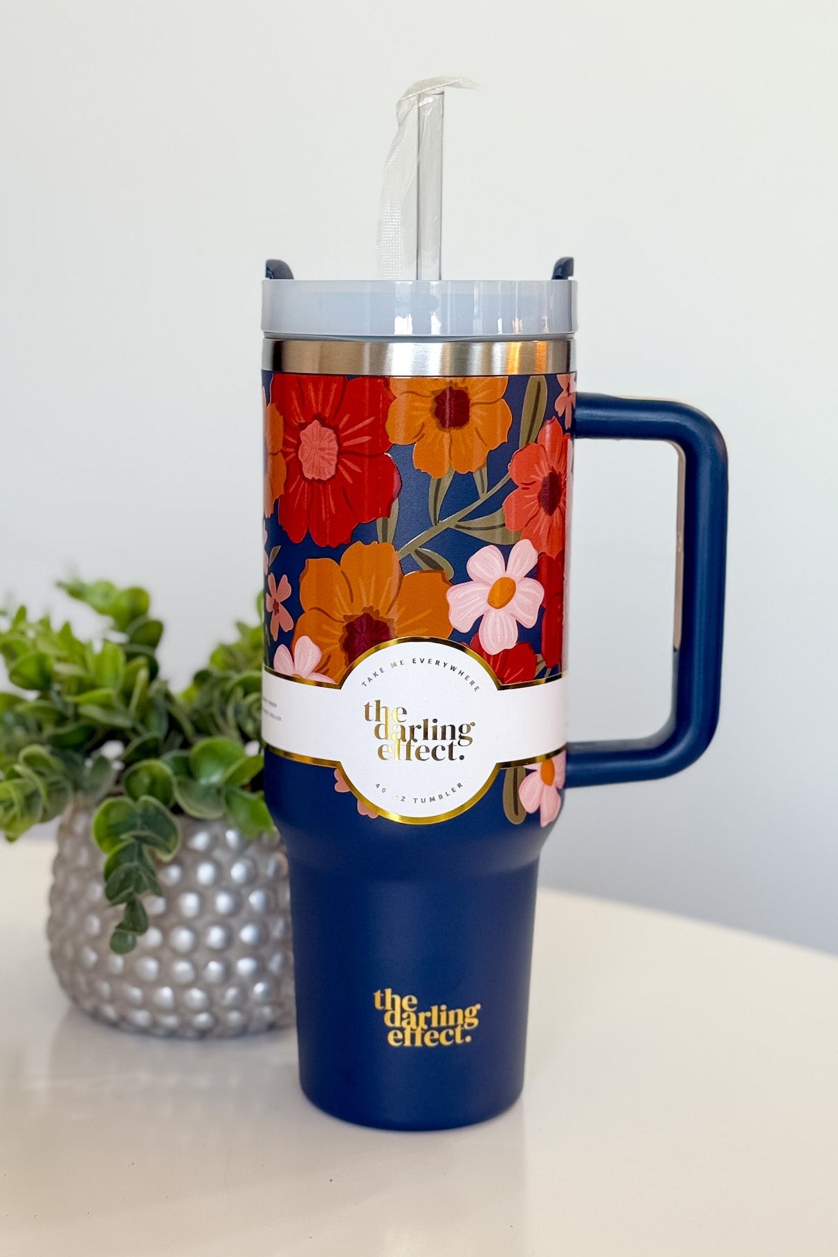 Floral-patterned tumbler with handle on a white surface, featuring 'the Darling Effect' branding.