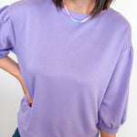 Person wearing a light purple sweater and blue jeans against a white background