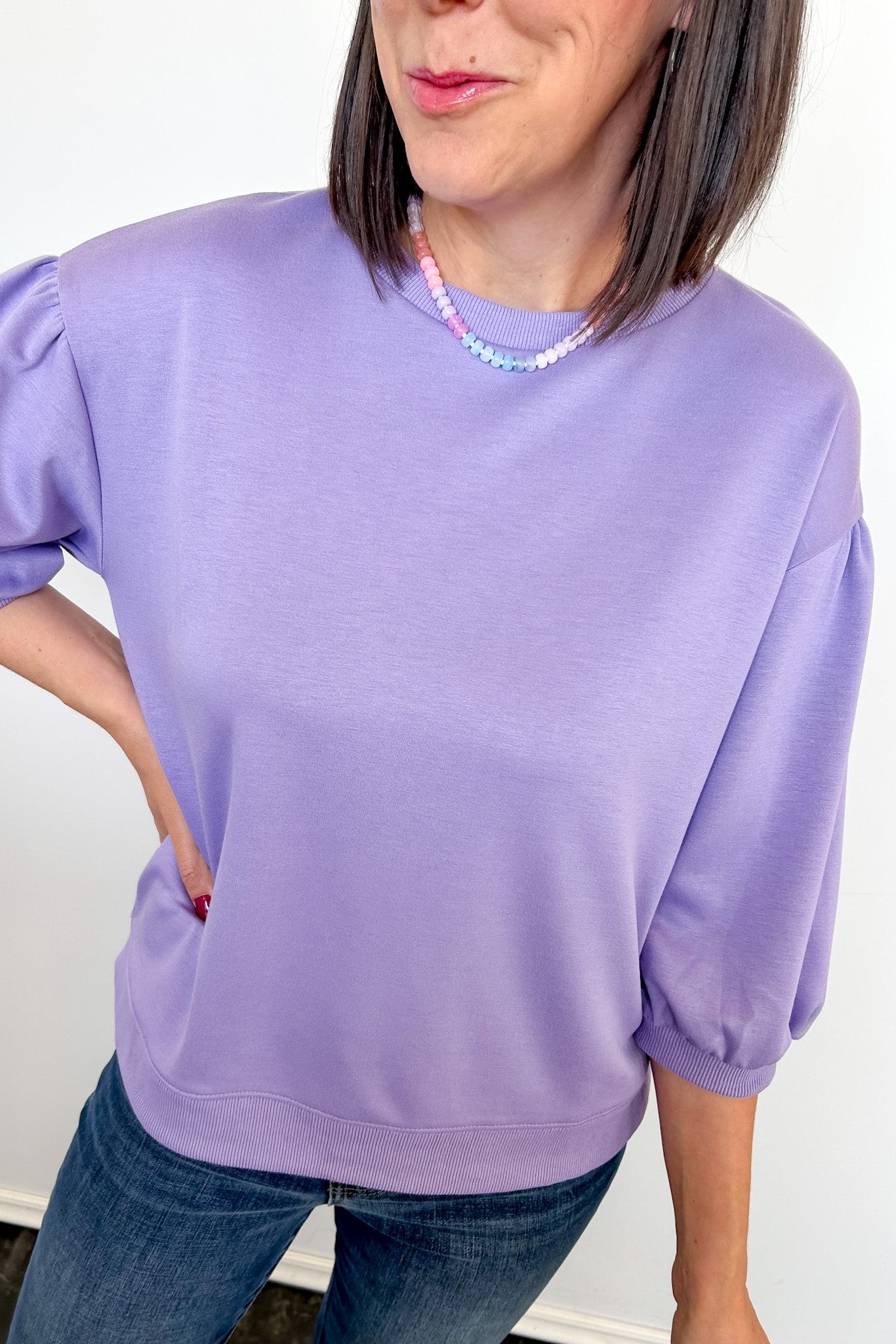 Person wearing a light purple sweater and blue jeans against a white background