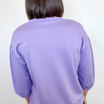 Person wearing a purple sweater against a white background
