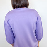 Person wearing a purple sweater against a white background