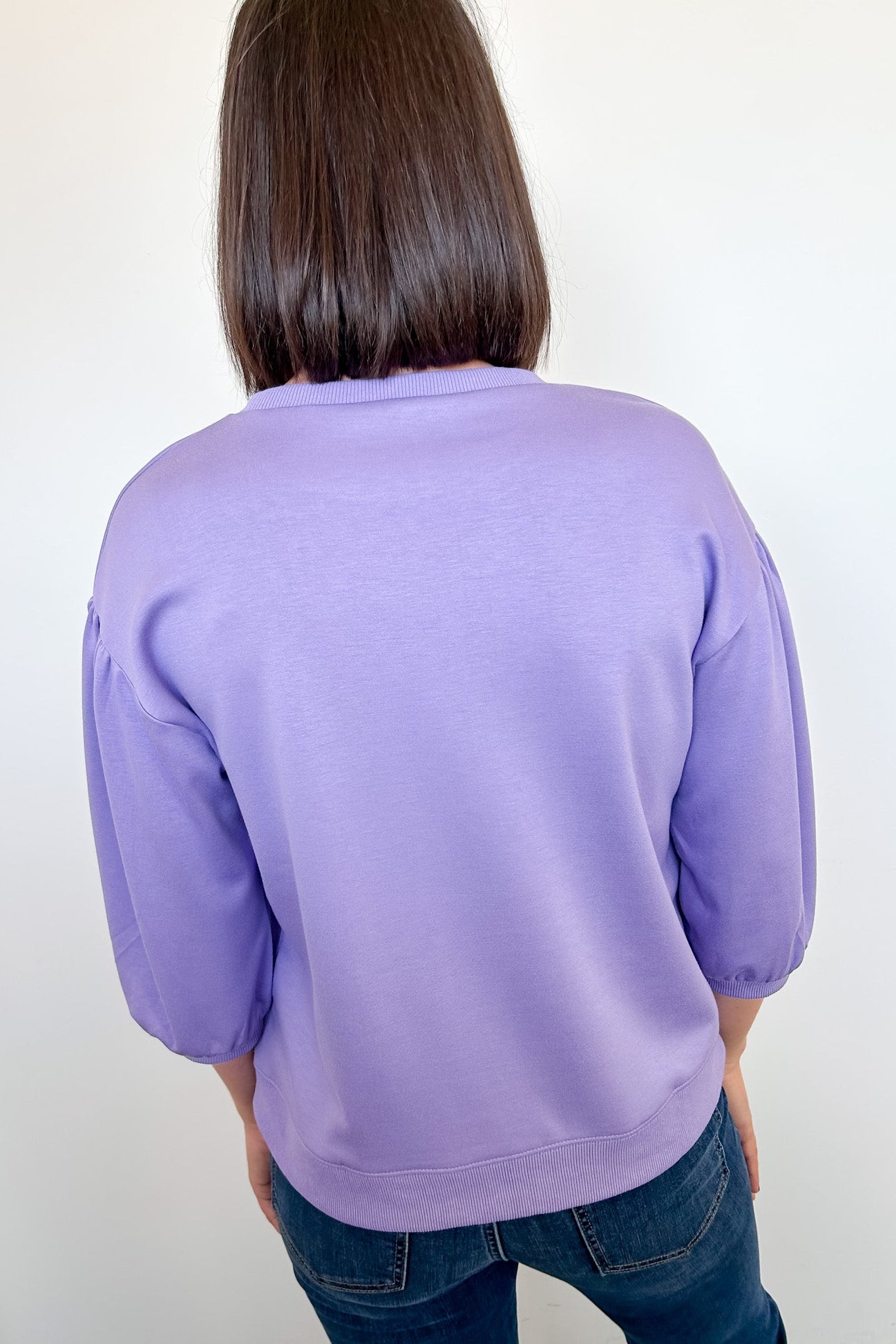 Person wearing a purple sweater against a white background