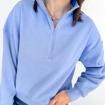Person wearing a light blue pullover with a quarter zip on a white background