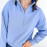 Person wearing a light blue pullover with a quarter zip on a white background