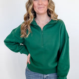Woman wearing a green pullover with a quarter zip on a white background