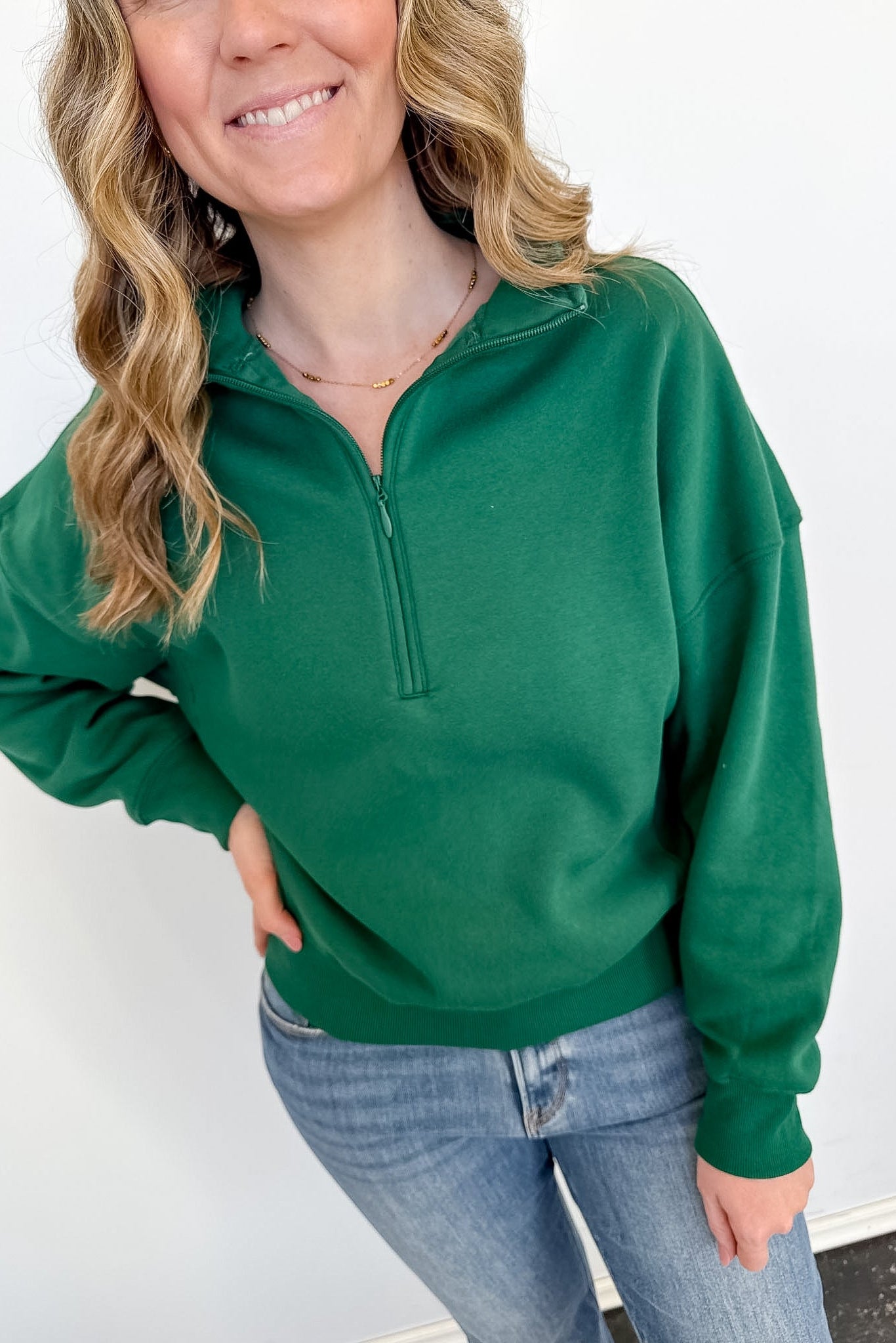 Person wearing a green pullover with a white background