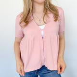 Babydoll style stop with open button up front. Short sleeve. Lightweight sweater material. Light pink in color.