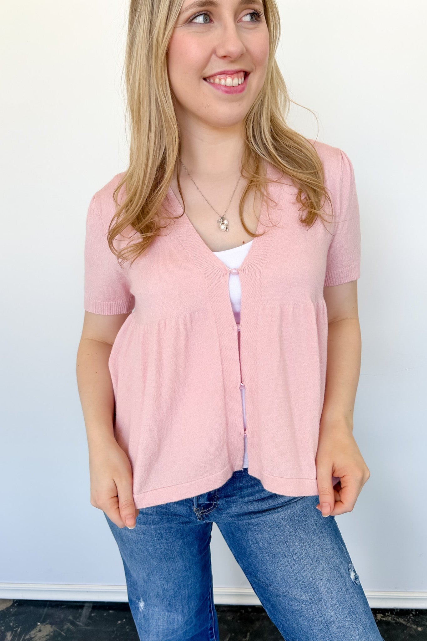 Babydoll style stop with open button up front. Short sleeve. Lightweight sweater material. Light pink in color.