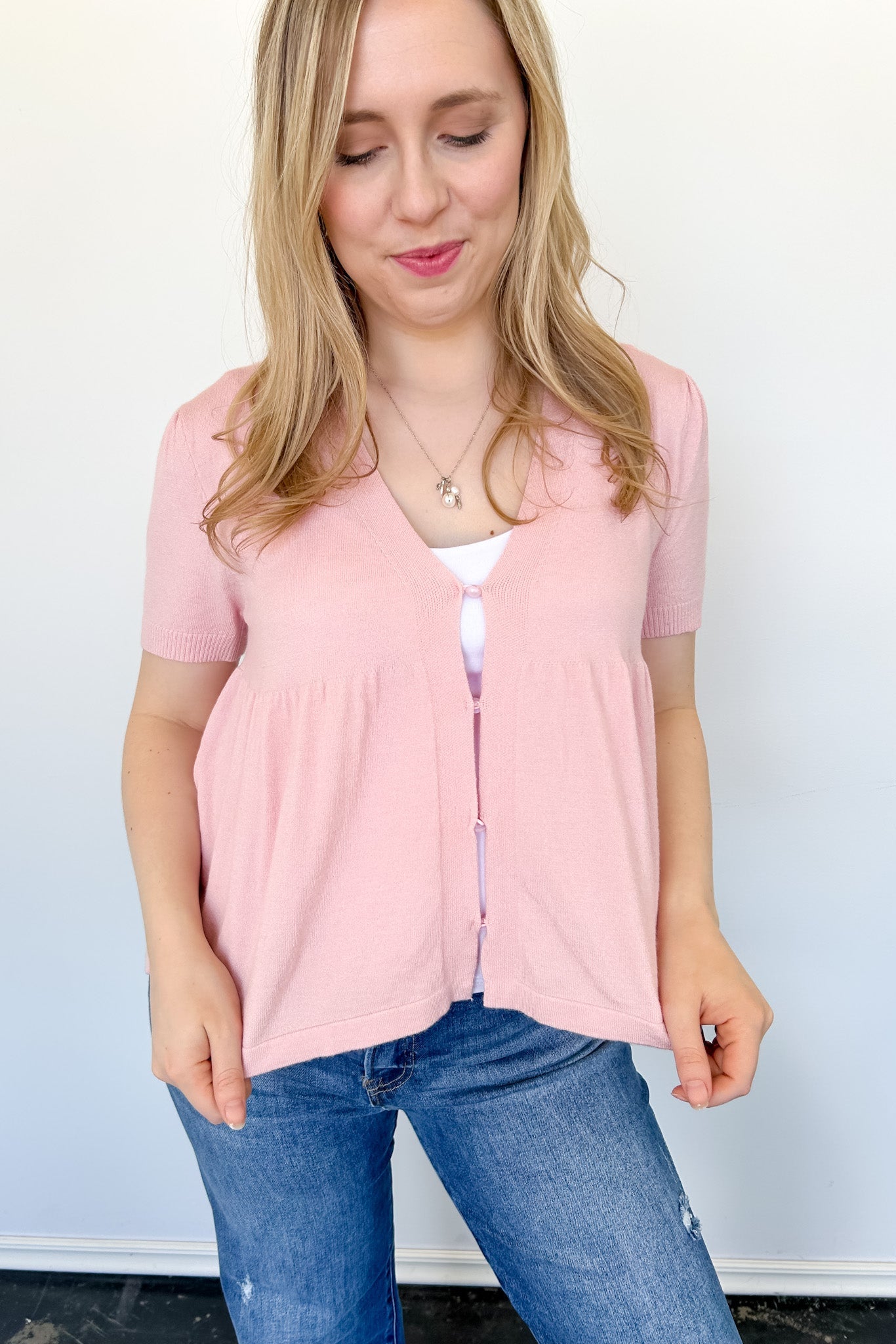 Babydoll style stop with open button up front. Short sleeve. Lightweight sweater material. Light pink in color.