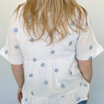 Woven top with light blue embroidered flowers. V neckline. Loose fit. Short sleeve. 