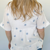 Woven top with light blue embroidered flowers. V neckline. Loose fit. Short sleeve. 