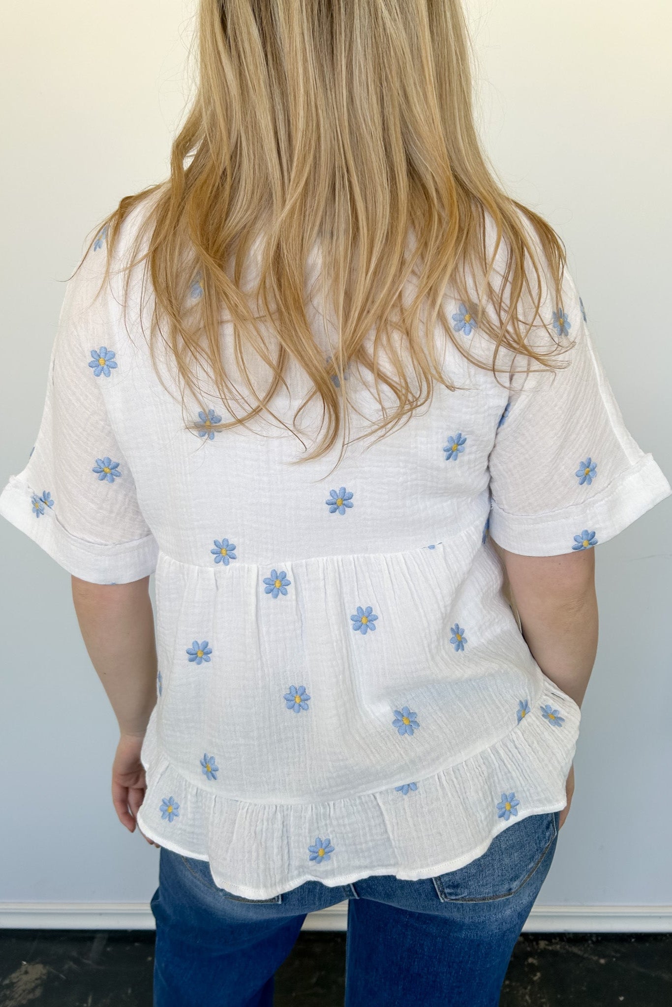 Woven top with light blue embroidered flowers. V neckline. Loose fit. Short sleeve. 
