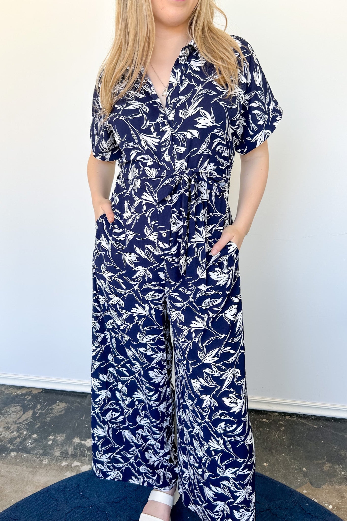 Tropical print jumpsuit. Navy with white print. Collared. Short sleeve. Loose fitting bottom. Pocket detailing. 