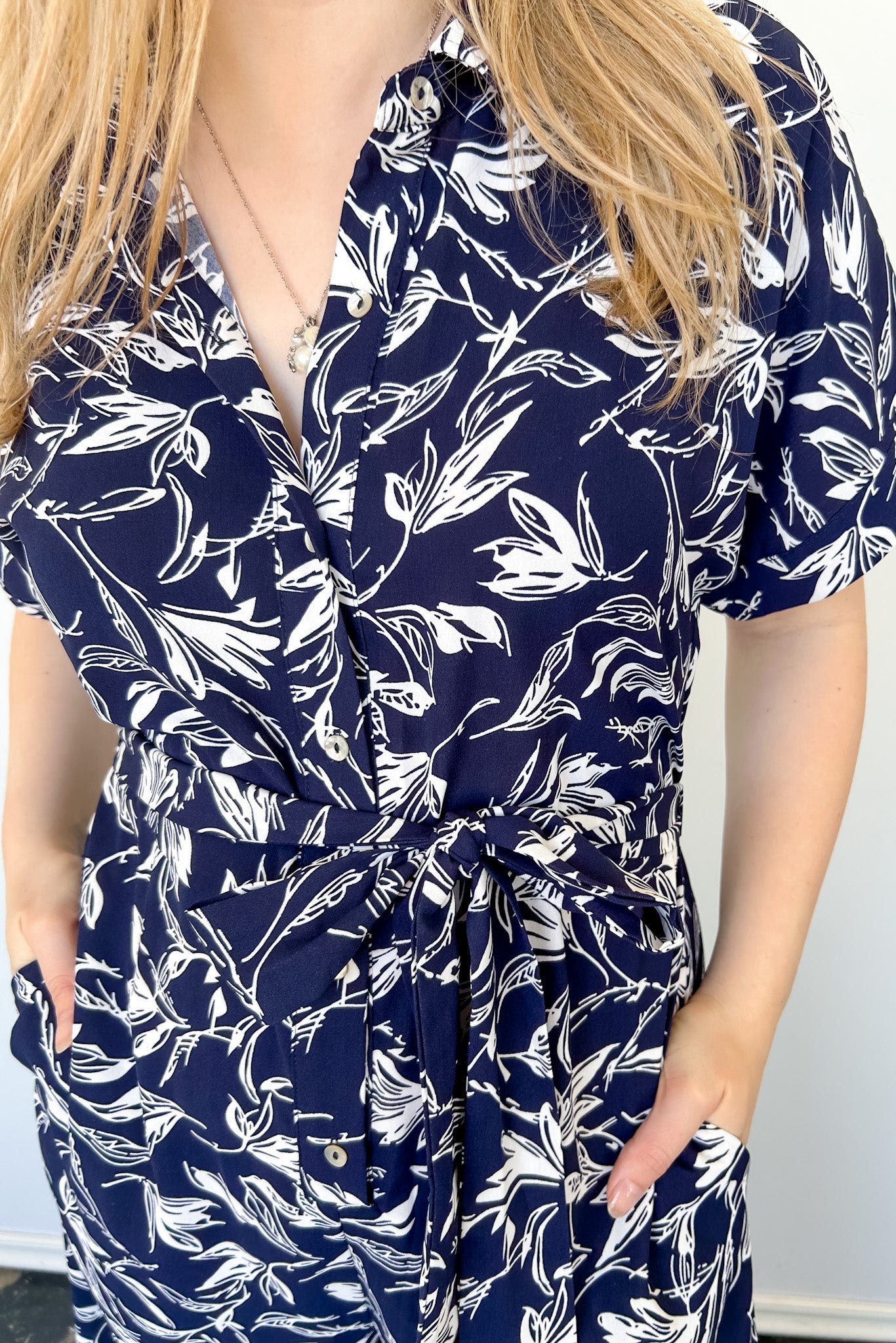 Tropical print jumpsuit. Navy with white print. Collared. Short sleeve. Loose fitting bottom. Pocket detailing. 