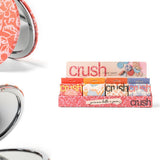 Compact mirror with floral design and 'crush' lip balm packaging on a white background