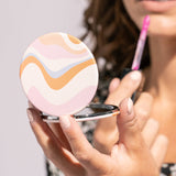Woman applying makeup with a compact mirror and pink lip balm.