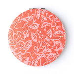 Round compact mirror with floral pattern on a white background
