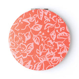 Round compact mirror with floral pattern on a white background