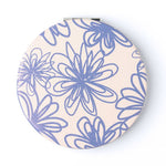 Round compact mirror with blue floral pattern on a beige background