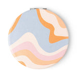 Round compact mirror with pastel wave pattern on a white background
