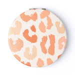 Compact mirror with orange and white leopard print on a white background