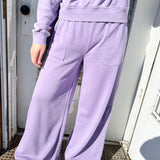 Person wearing a purple tracksuit standing on a doorstep.