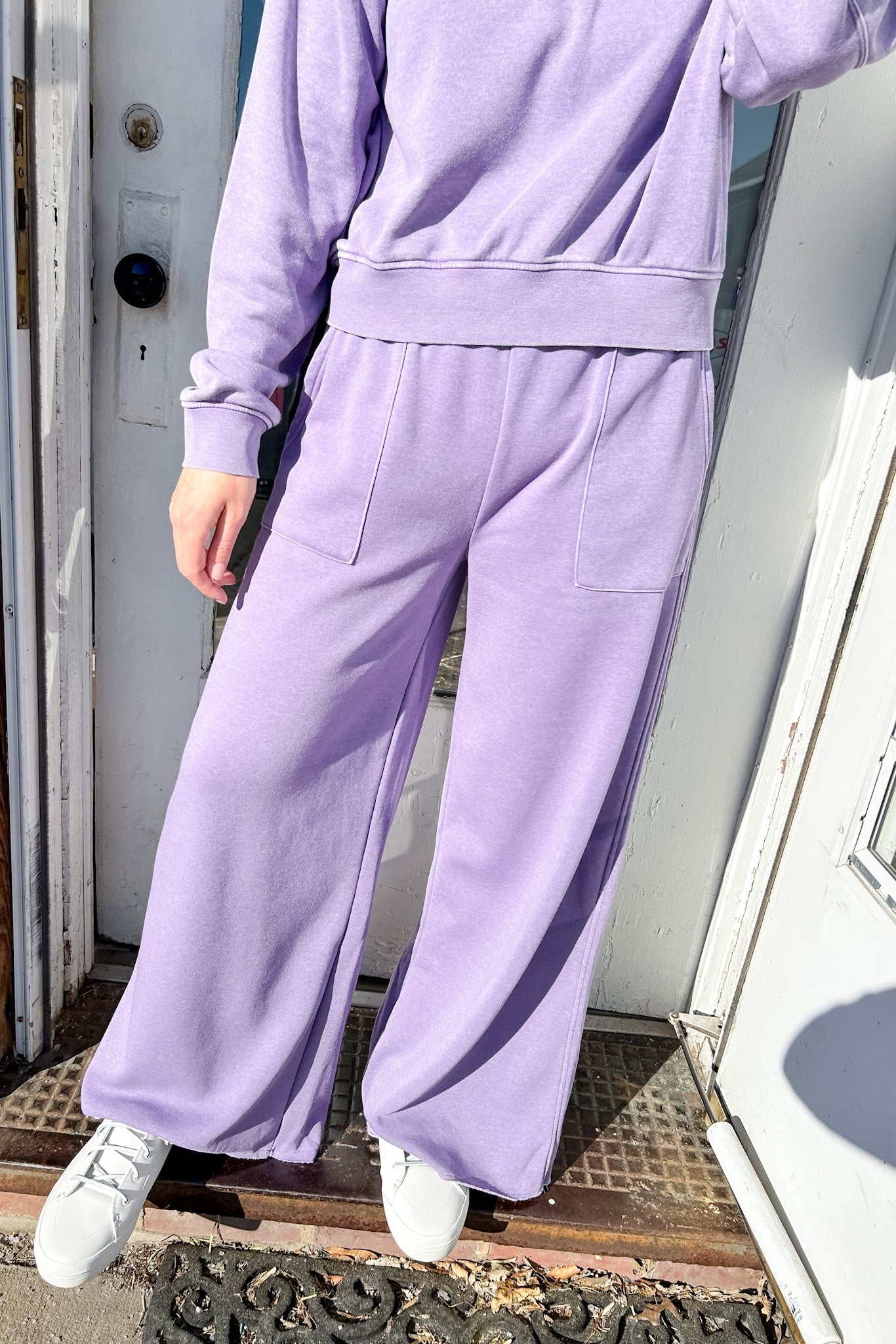 Person wearing a purple tracksuit standing on a doorstep.