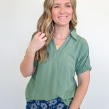 Woman wearing a green top and blue floral pants against a white background