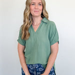 Woman wearing a green shirt and blue floral pants against a white background