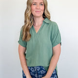 Woman wearing a green shirt and blue floral pants against a white background