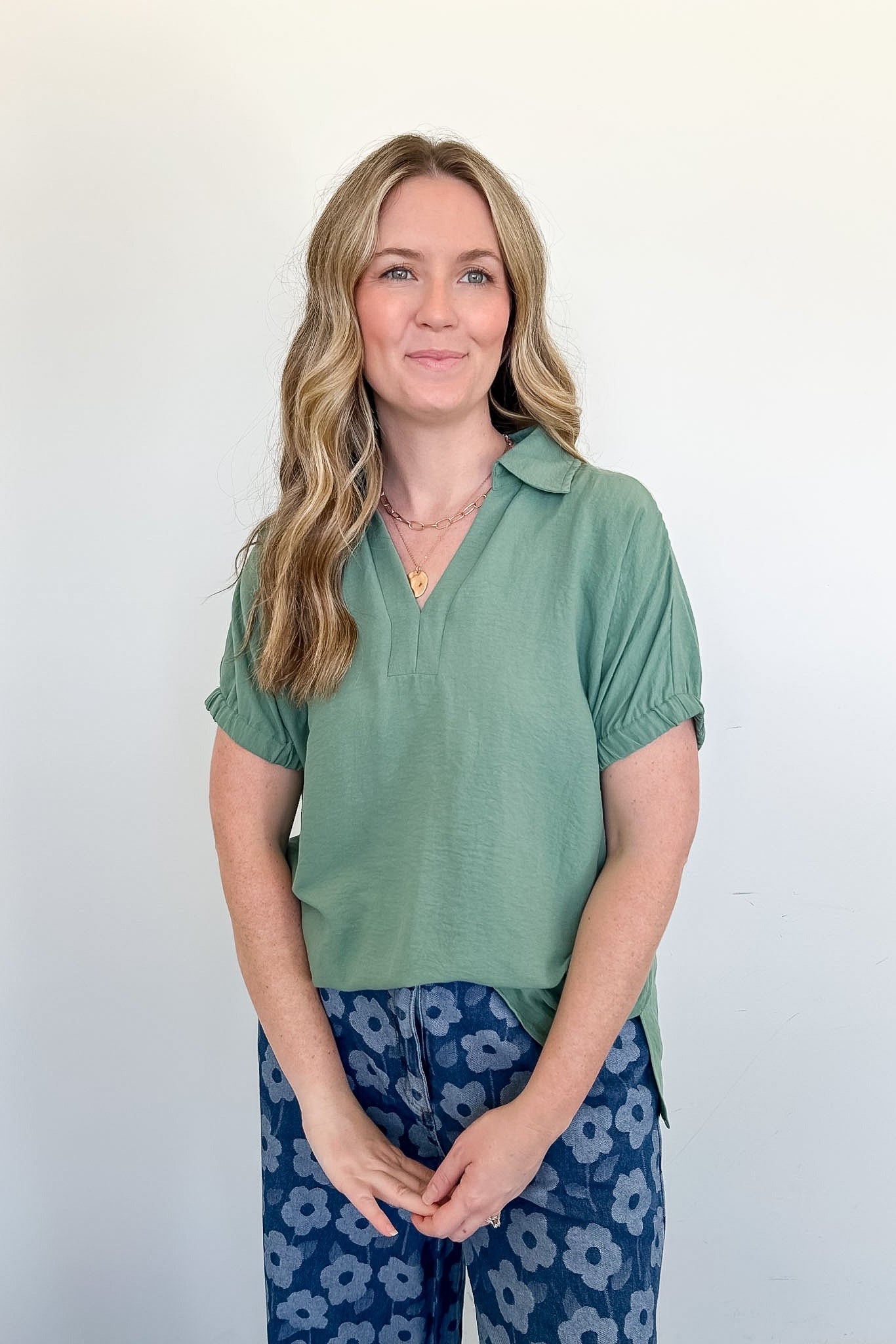 Woman wearing a green shirt and blue floral pants against a white background