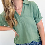 Woman wearing a green top and blue floral pants against a white background