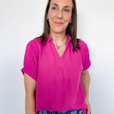 Woman wearing a pink shirt and floral pants against a white background