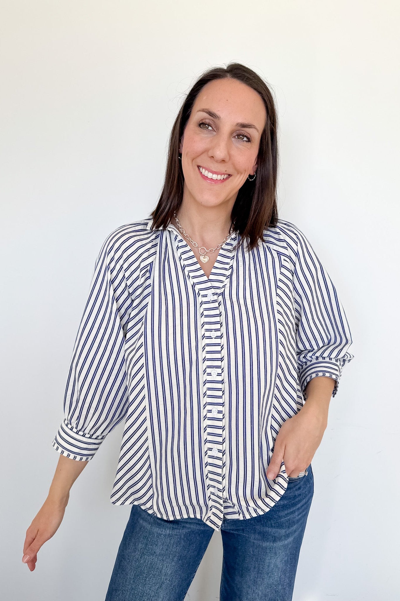 Woman wearing a striped shirt and jeans against a white background