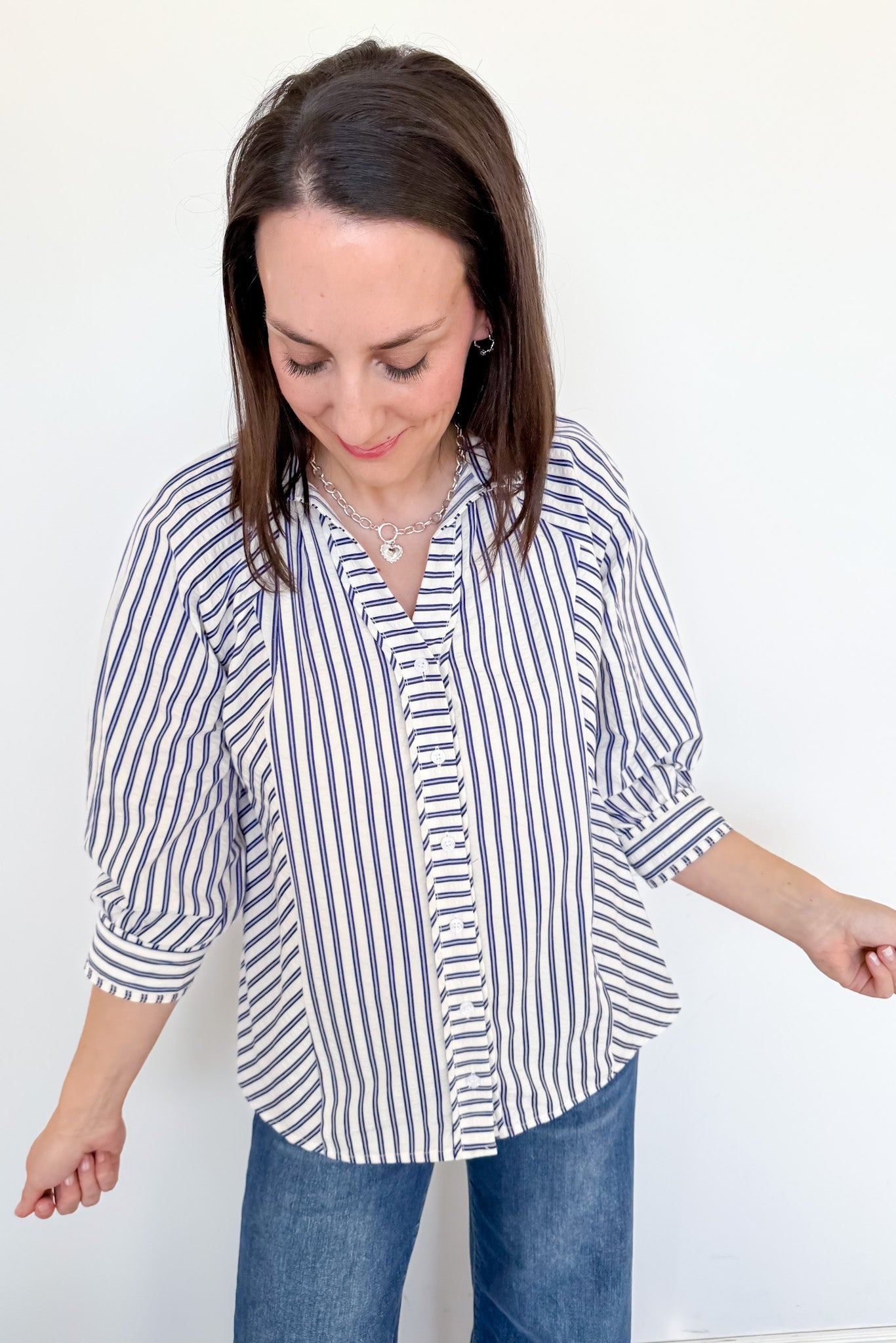 Woman wearing a striped shirt and jeans against a white background