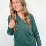 Woman wearing a green sweater and blue jeans against a white background