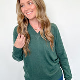 Woman wearing a green sweater and blue jeans against a white background
