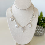Silver necklace with charms on a white bust against a light background