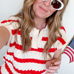 Woman wearing a red and white striped dress with sunglasses, holding an American flag.