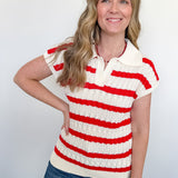 A woman wearing a striped sweater in front of a white wall.