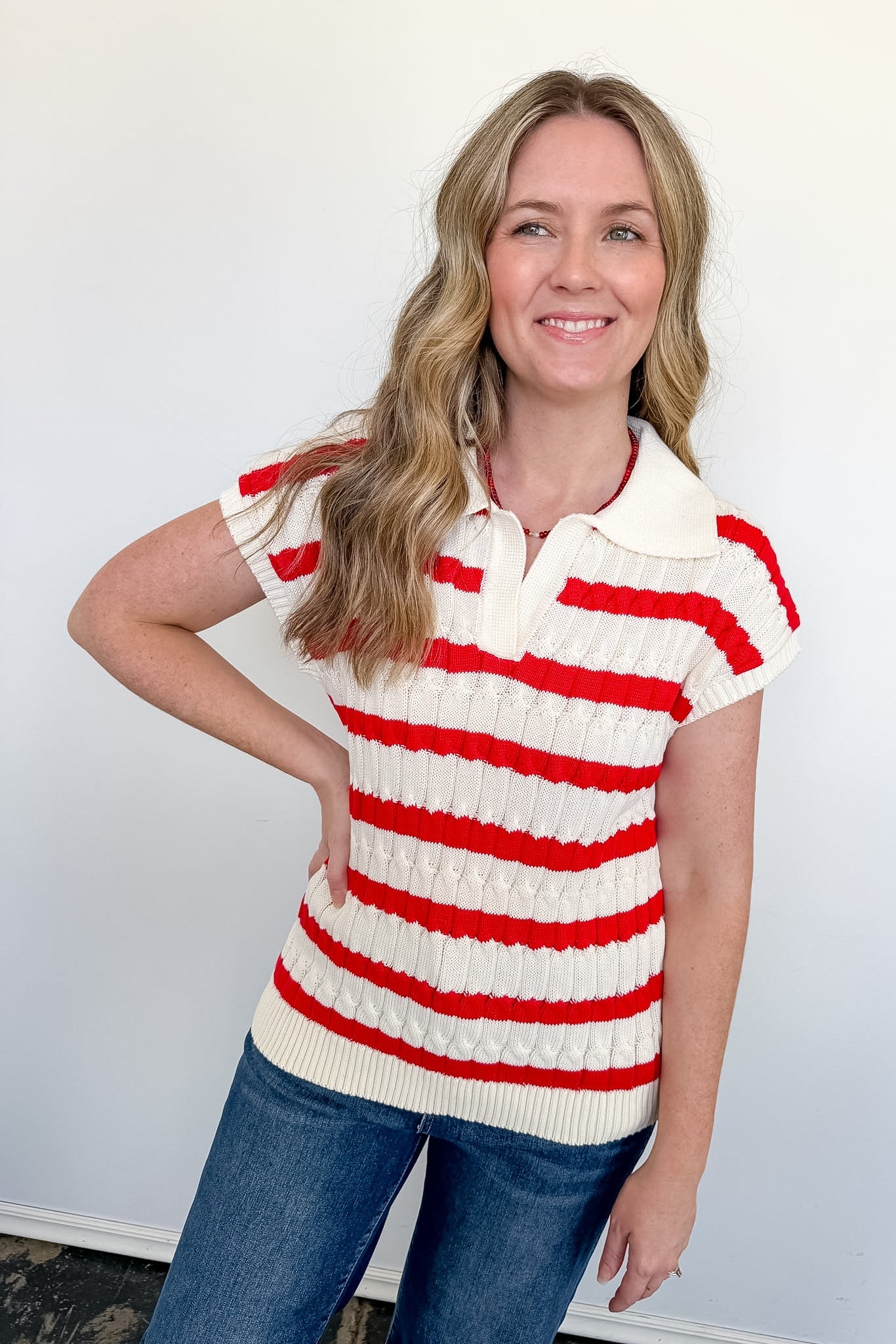 A woman wearing a striped sweater in front of a white wall.