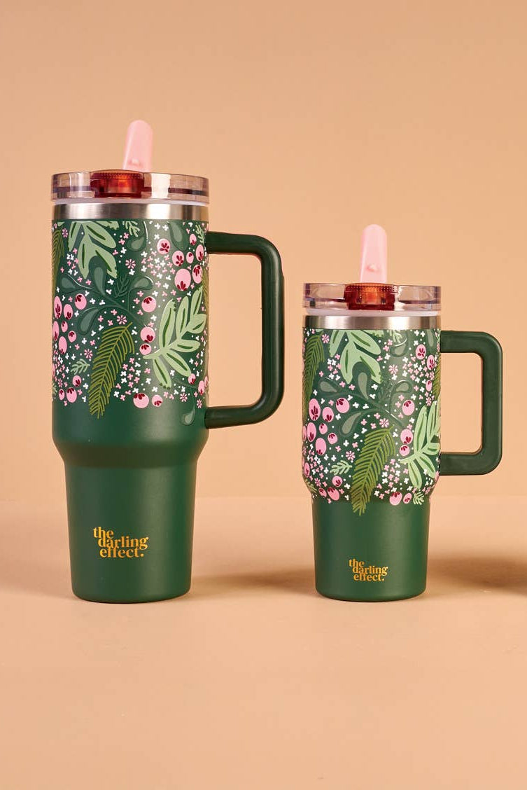 Set of three green tumblers with floral designs on a beige background