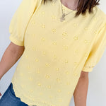 Person wearing a yellow blouse with floral patterns against a white background
