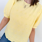 Person wearing a yellow blouse with floral patterns against a white background