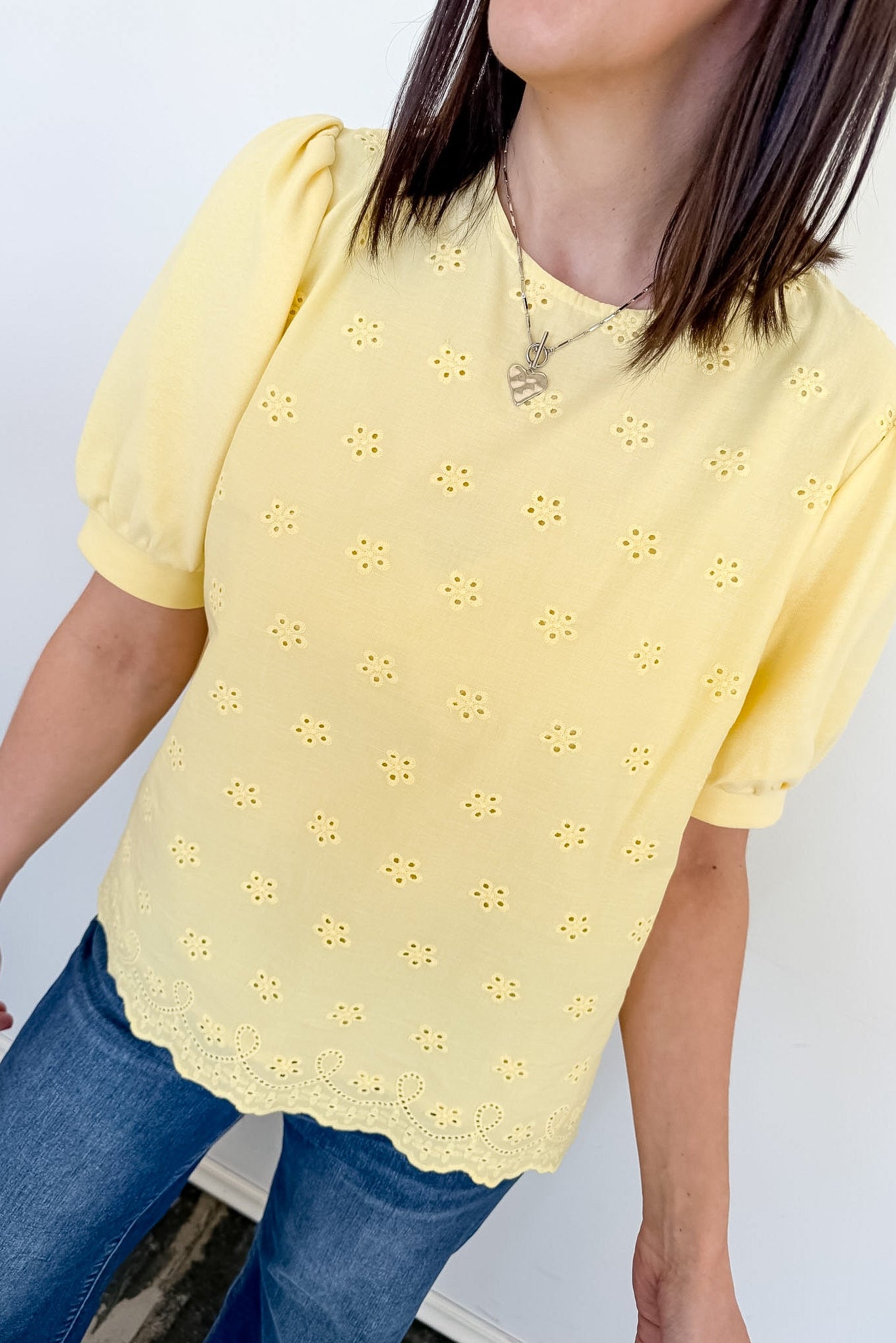 Person wearing a yellow blouse with floral patterns against a white background