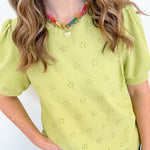 Person wearing a light green blouse with star patterns and blue jeans on a white background