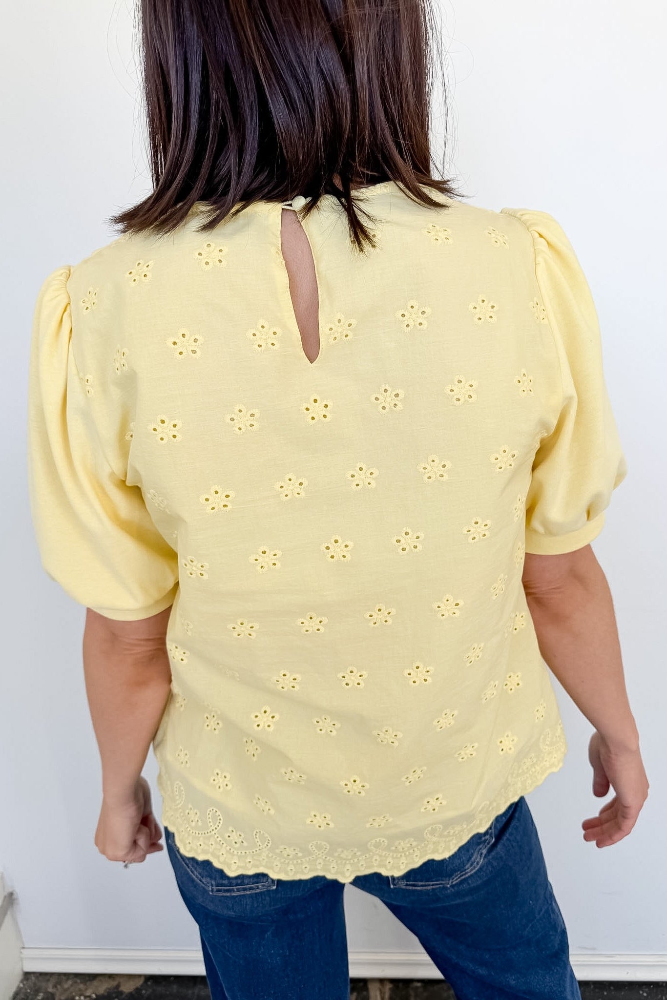 Person wearing a yellow blouse with floral patterns against a white background