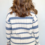 Person wearing a striped sweater with blue and white horizontal stripes against a plain background