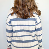 Person wearing a striped sweater with blue and white horizontal stripes against a plain background